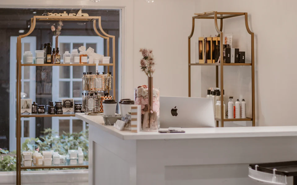 Espace d’accueil clair et élégant d’un institut de beauté aux étagères dorées